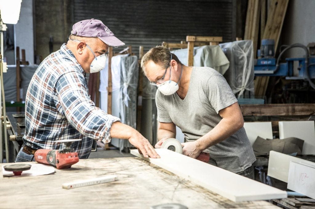 Zwei Mitarbeiter bei der Handbearbeitung einer Natursteinfensterbank